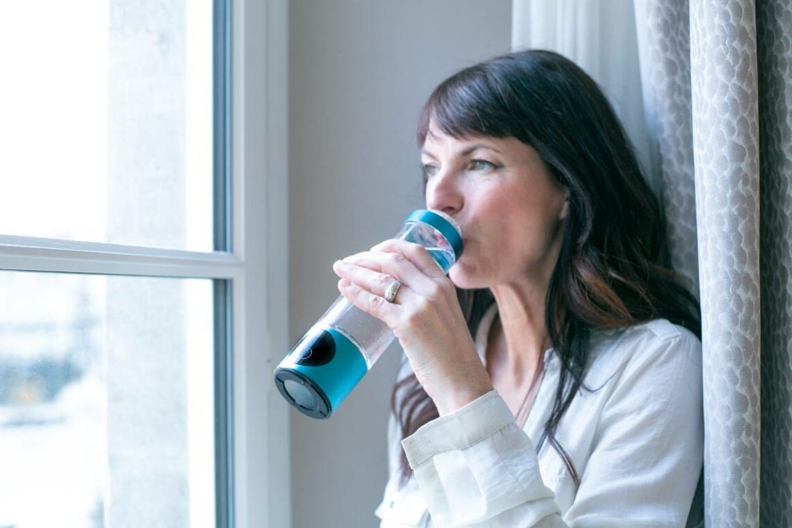 Femme buvant de l’eau hydrogénée avec la gourde Climsom Pure pendant sa phase prémenstruelle