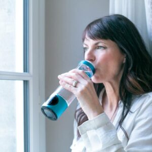 Femme buvant de l’eau hydrogénée avec la gourde Climsom Pure pendant sa phase prémenstruelle